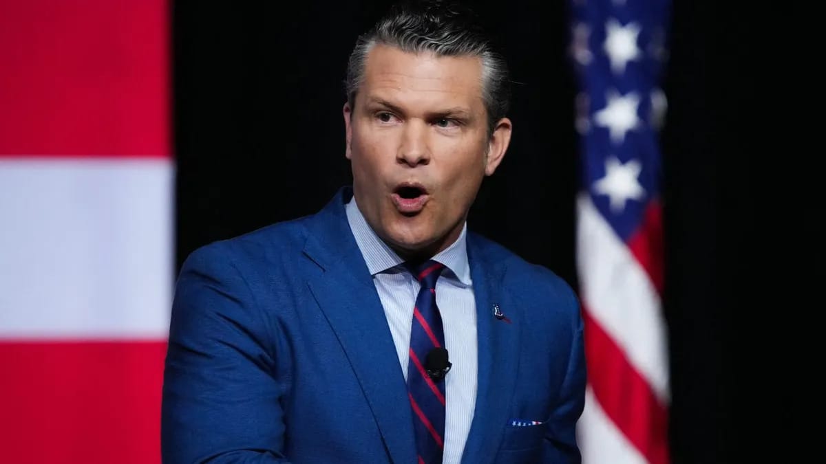 A white man wearing a blue suit is pictured speaking.
