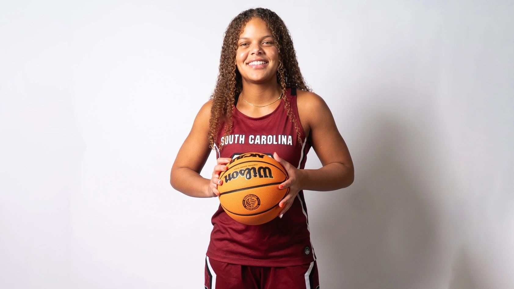 High School recruit Jerzy Robinson poses for a portrait wearing a South Carolina jersey and holding a basketball.