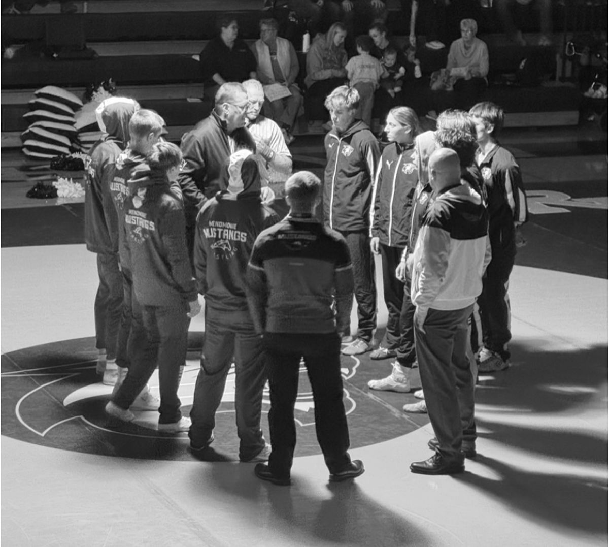 Wrestlers meet at the center of the mat before a match.