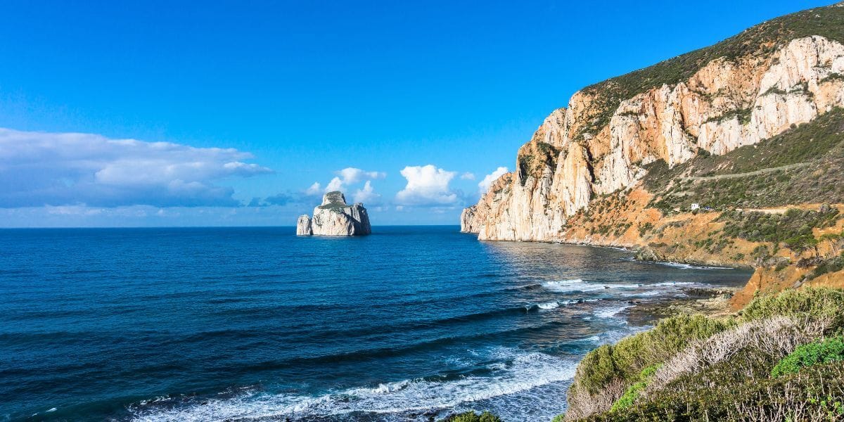 Tall limestone sea stack rising from deep blue water near Sardinia’s southwestern coast