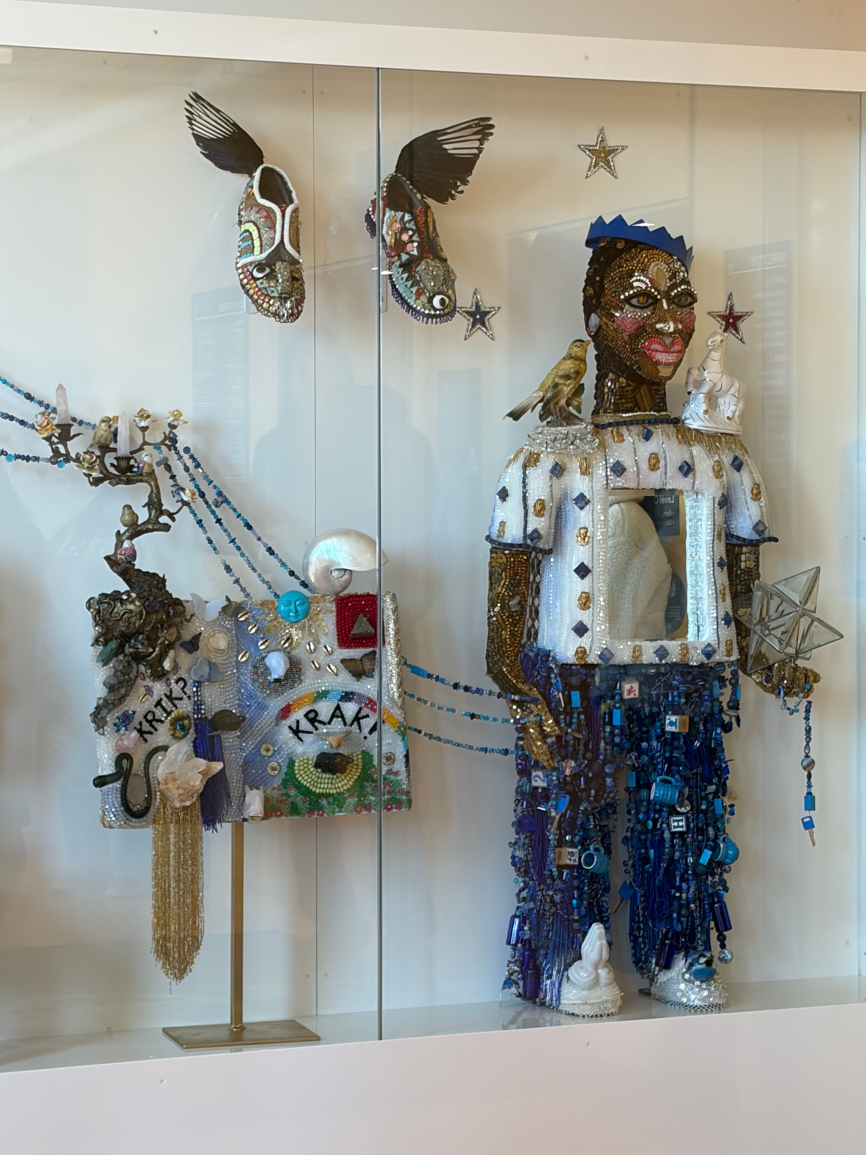 Beaded found object sculptures in a glass vitrine