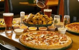 A table with pizza, chicken and other food items.