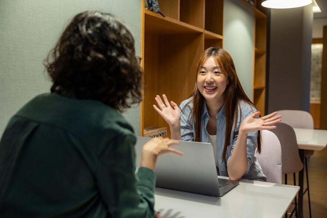 Two female employees sitting down facing each other during work meeting in relaxing office environment