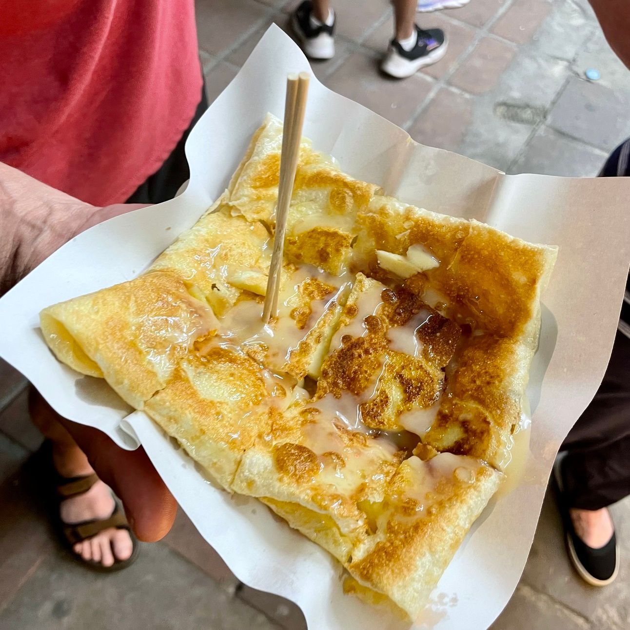 A crispy, golden pastry called a "roti" drizzled with sweetened condensed milk.