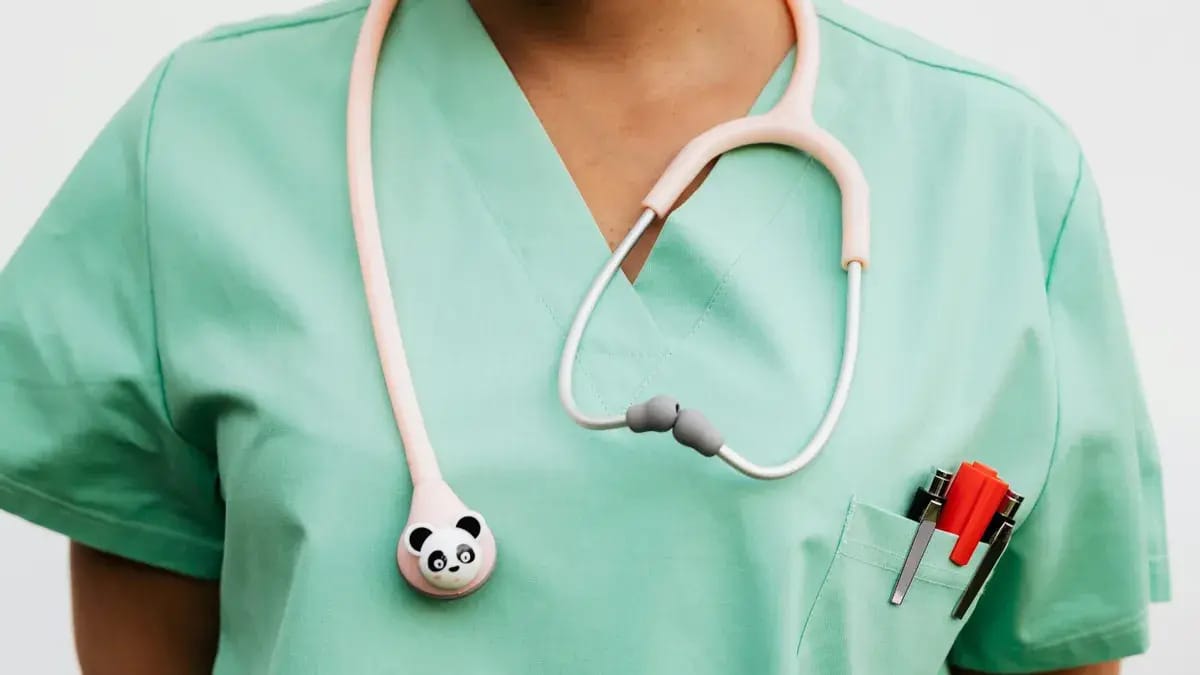 A person wearing green scrubs has a panda stethoscope hanging around their neck.