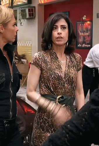 Gif da série Tapas e Beijos. Duas mulheres de uns 30 anos estão paradas na rua. Uma move a mão enquanto fala “o tempo, Sueli”. Ao seu lado, a amiga a olha, confusa.