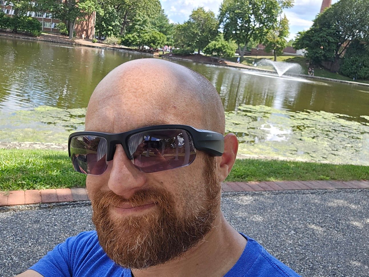 A selfie of me in front of a pond with a fountain on a sunny day