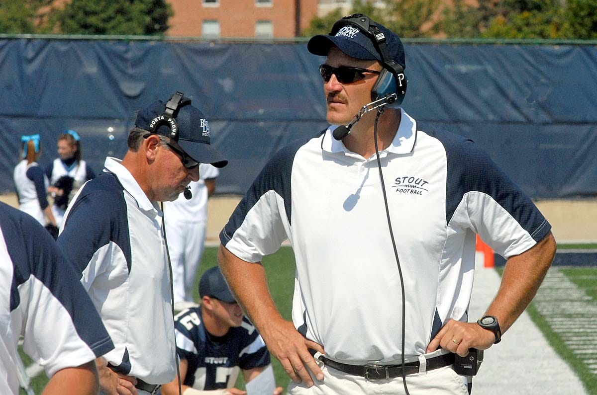 A football coach observes his bench. 
