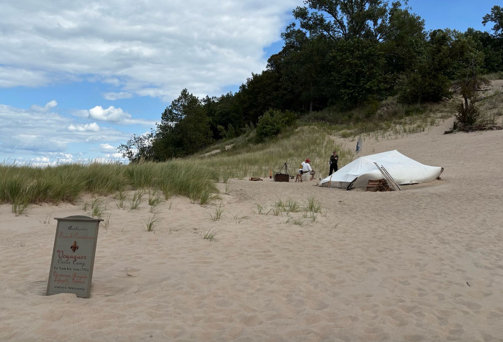 A Picture of people camping in a tent on beach with sign explaining what they are doing in foreground 