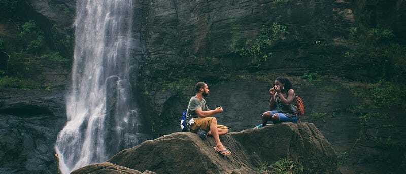 Two people sitting quietly under a waterfall, soaking in the stillness — a moment of peace, presence, and unspoken connection.