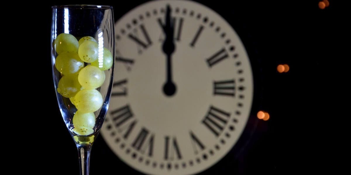 grapes in a glass in front of a clock - Photo: phatymak's studio/Shutterstock