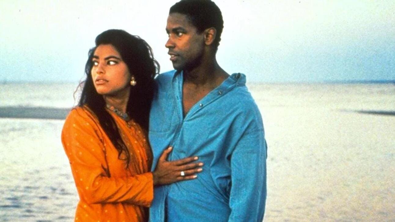 Screenshot of Denzel Washington in Mississippi Masala, wearing a casual shirt, standing outdoors with a thoughtful expression.