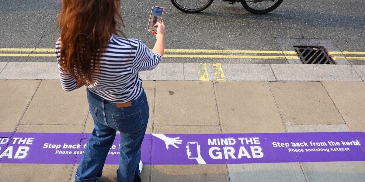 a woman holding her cell phone over a sign