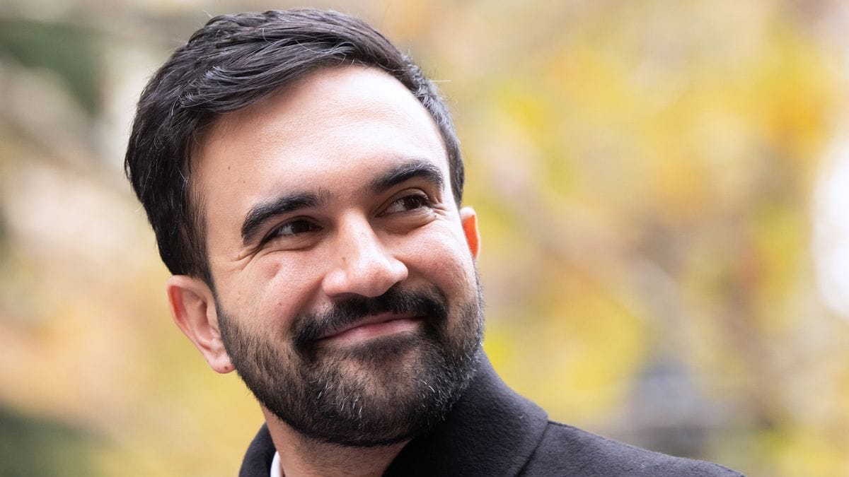 A South Asian man smiles outside.