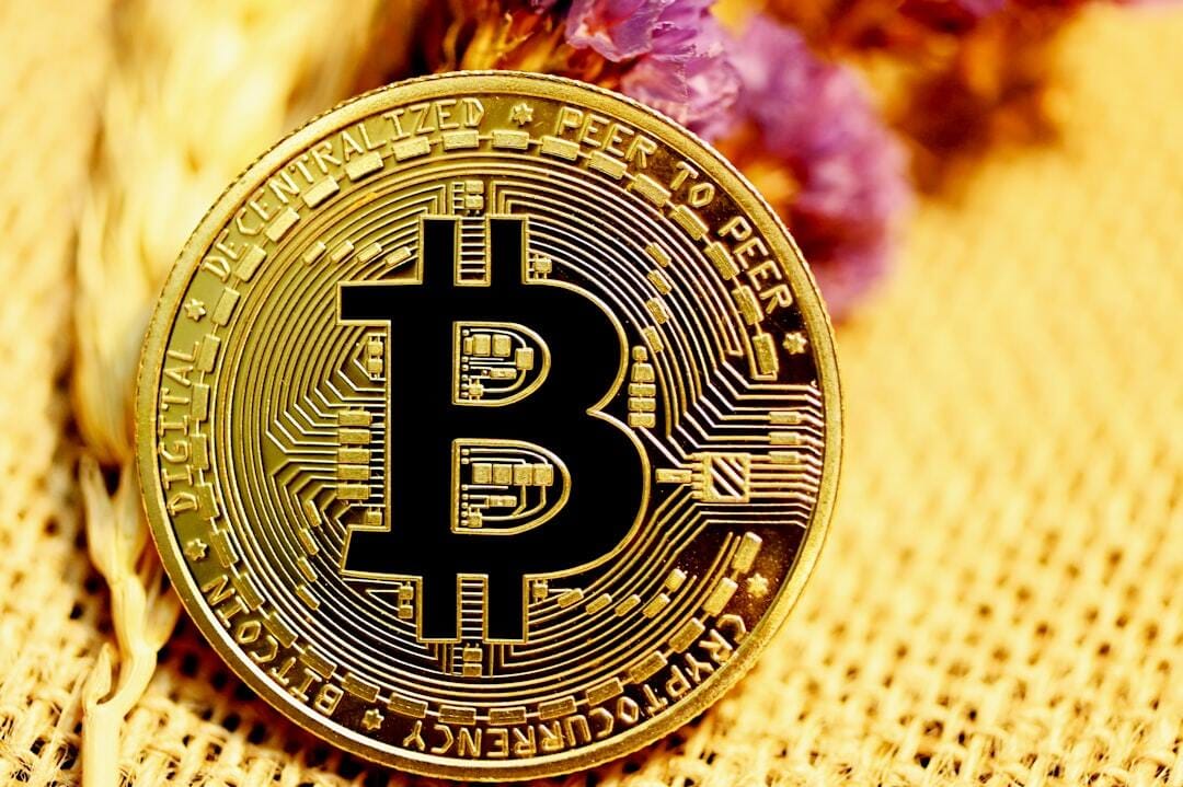 A bitcoin with a purple flower on a woven surface