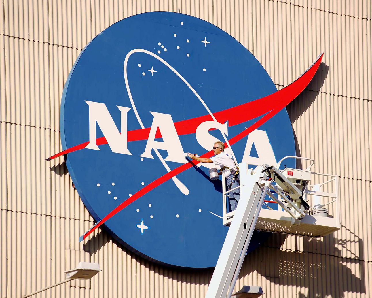 A painter touches up the iconic NASA emblem on the Flight Research Building at NASA’s Glenn Research Center. Known as “the meatball,” the distinctive blue logo has made the hangar one of the center’s most recognizable landmarks.