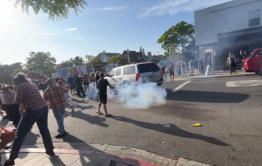 A cloud of smoke lingers outside a San Diego restaurant as Immigration and Customs Enforcement agents use a flash-bang device to disperse a crowd during a May 2025 raid.