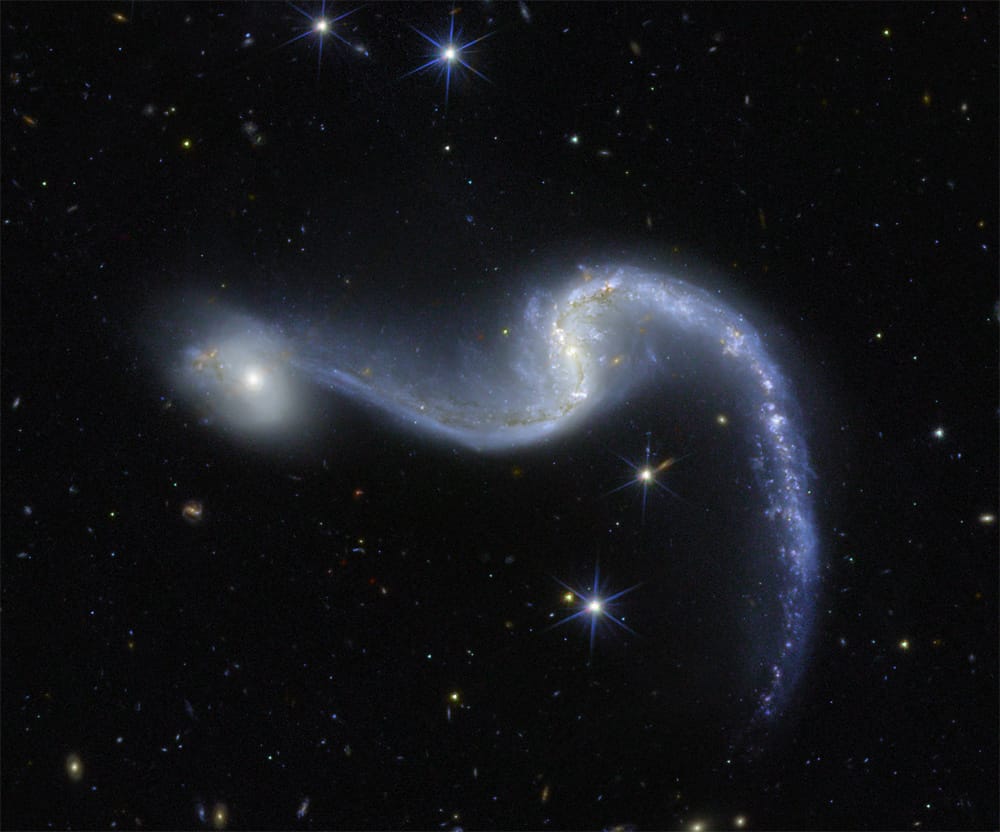 A spiral galaxy with wide flung arms and a smaller, more compact galaxy right next to it.