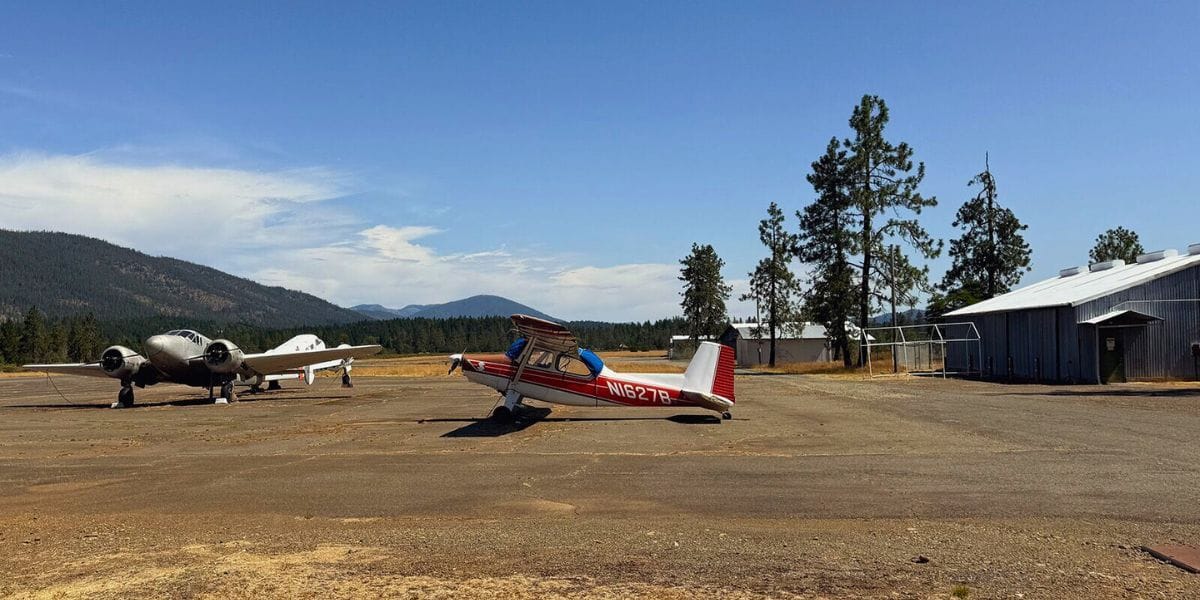 two small airplanes on a run way by mountains