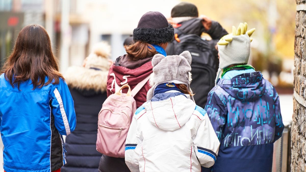 Children can be seen outside walking in a group with their backs turned to the camera.