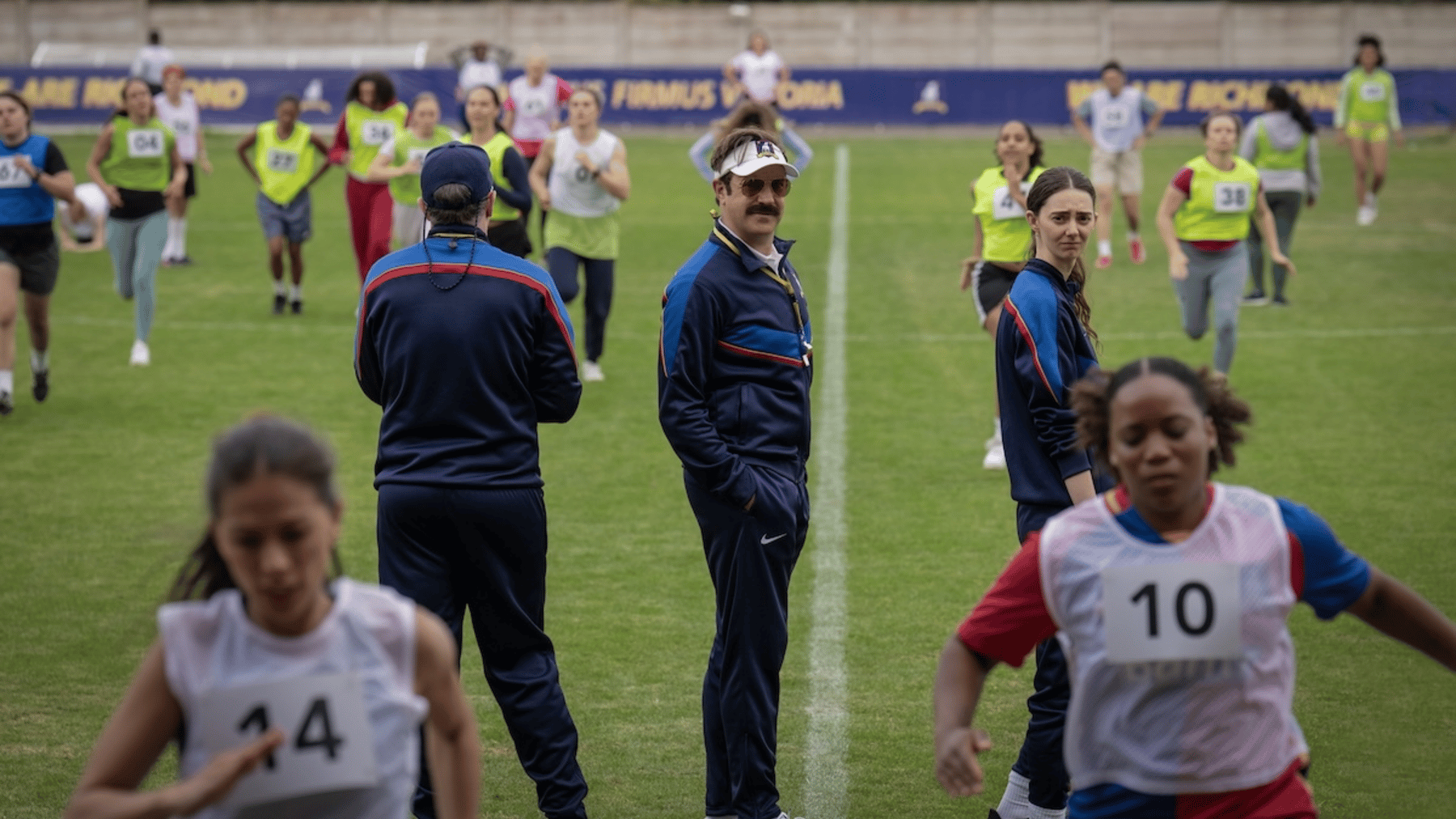 Jason Sudeikis as Ted Lasso watches women's football try outs in a still from Ted Lasso.