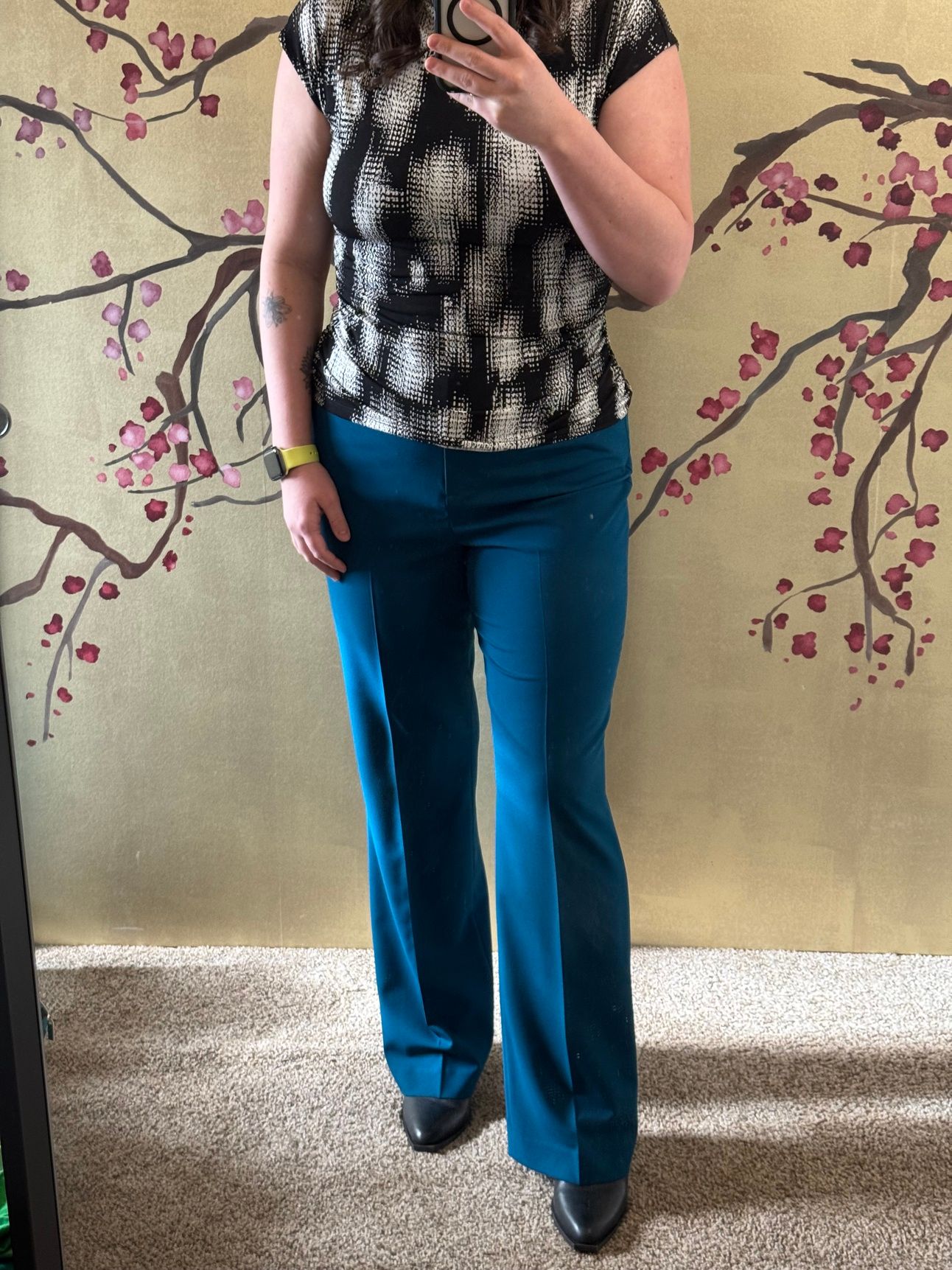 photo of a femine body in blue slacks and black and white abstract pixel pattern shirt