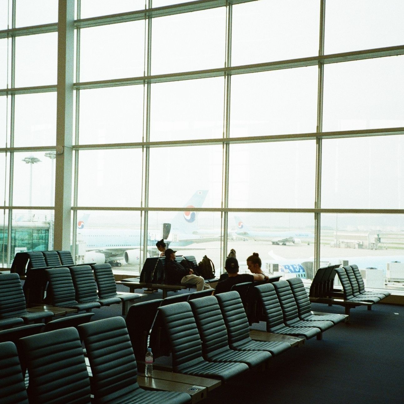 People sit and wait at a boarding gate at Incheon International Airport.