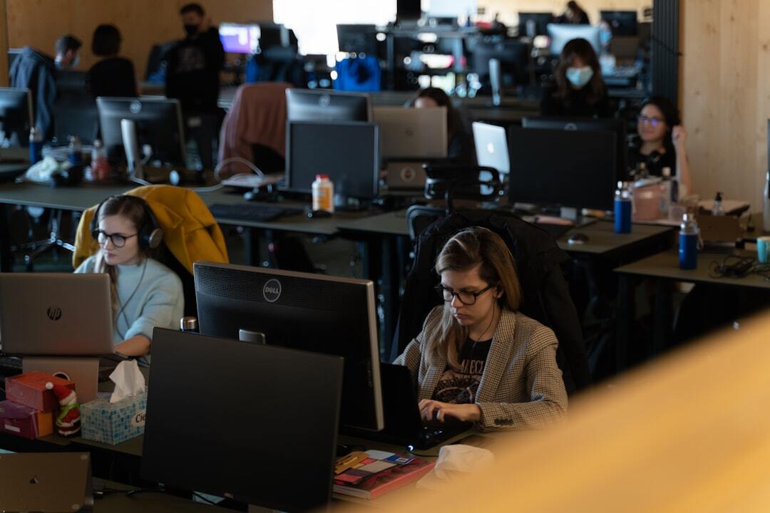 Female colleagues working on computers in crowded office.