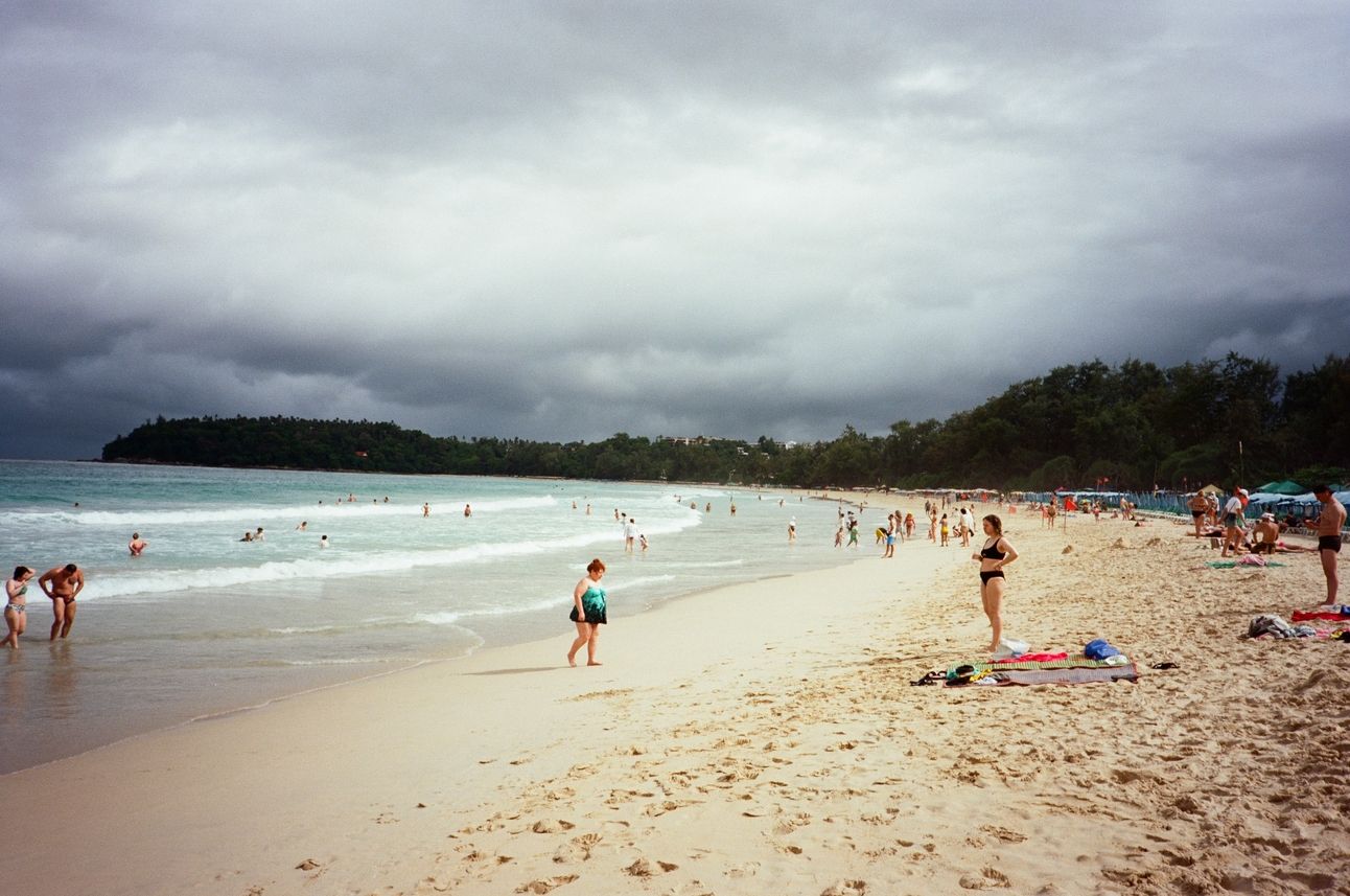 The cove of Kata beach with tourists enjoying the sun and waves.