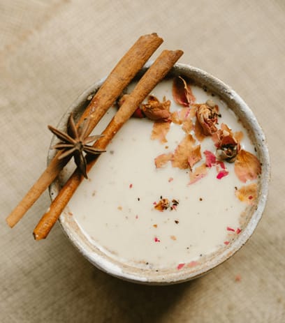 A bowl of white melted ice cream, with cinnamon stick garnishes