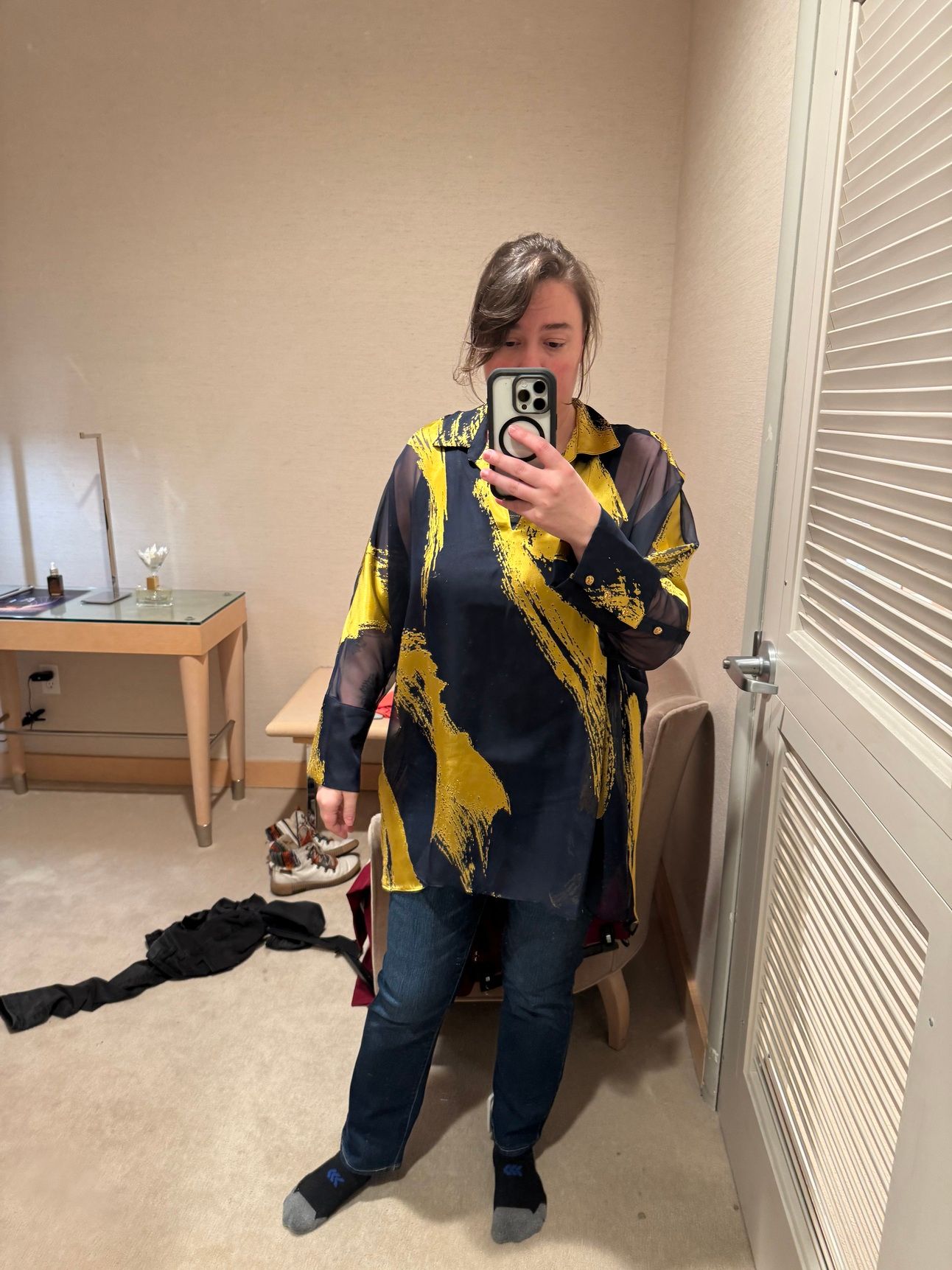 photo of a femine body in jeans and an oversized abstract black and gold blouse