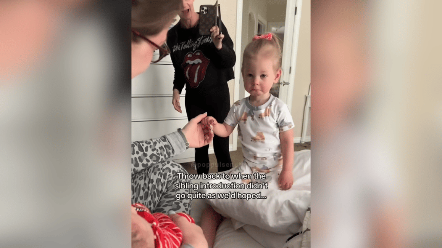 A sad-looking toddler gets introduced to her newborn sibling