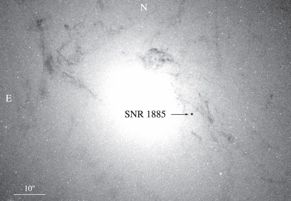 The fuzzy nucleus of the Andromeda Galaxy is surrounded by zillions of stars. One spot is black, and indicated to be SN 1885A.