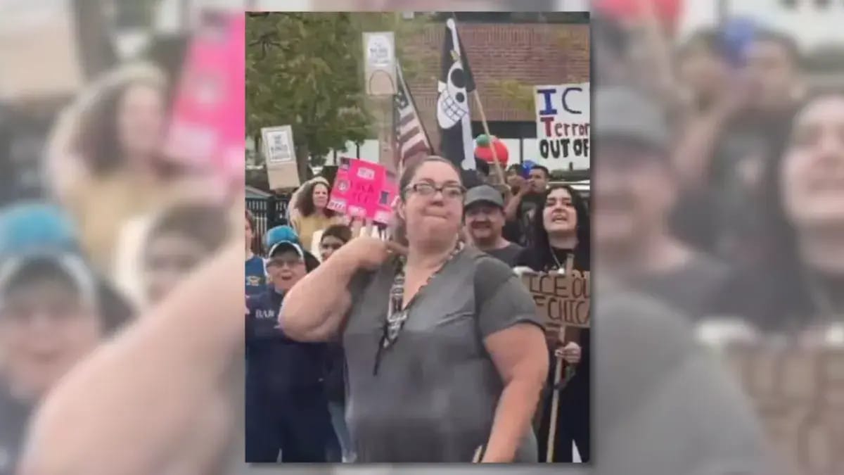 A person is shown standing in front of crowd holding signs. Many of those signs appear to mention ICE. 