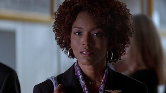Screenshot of Angela Bassett in The Score, wearing business casual attire, looking calmly assertive in a sleek, upscale apartment.