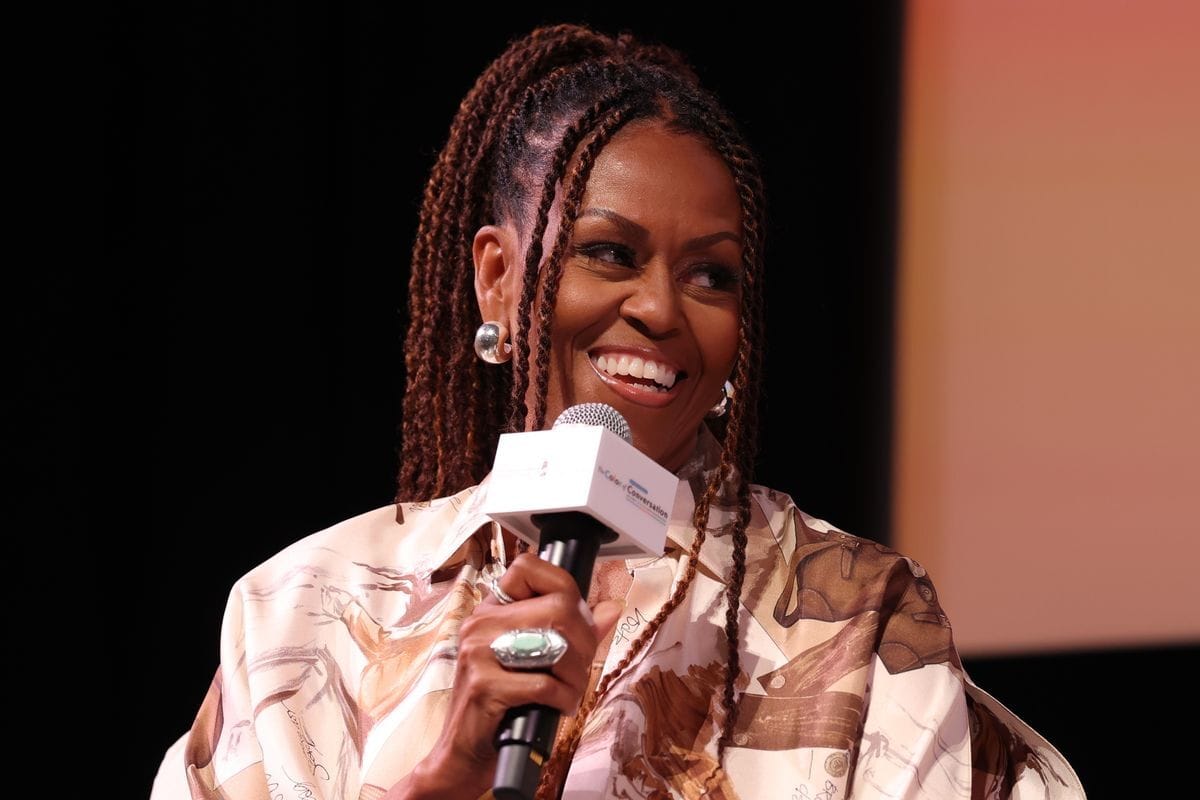 A Black woman holding a microphone smiles as she looks to the right.