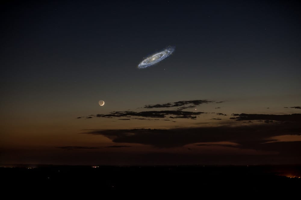The Andromeda galaxy hangs in the sky in a composite photo near the Moon, to give a sense of scale.