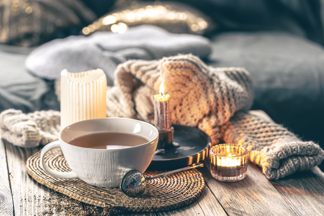 cozy-home-composition-with-cup-tea-candles-knitted-element