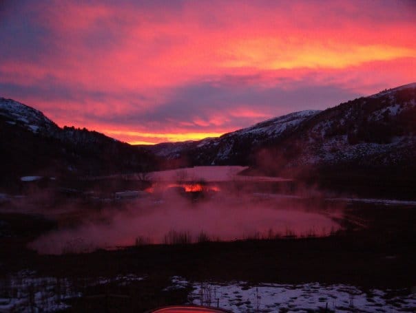 pink and purple sunset behind mountains at maple grove hot springs in thatcher idaho