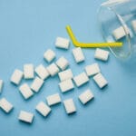 Sugar Cubes In Glass Cup On The Pastel Blue Background. Concept