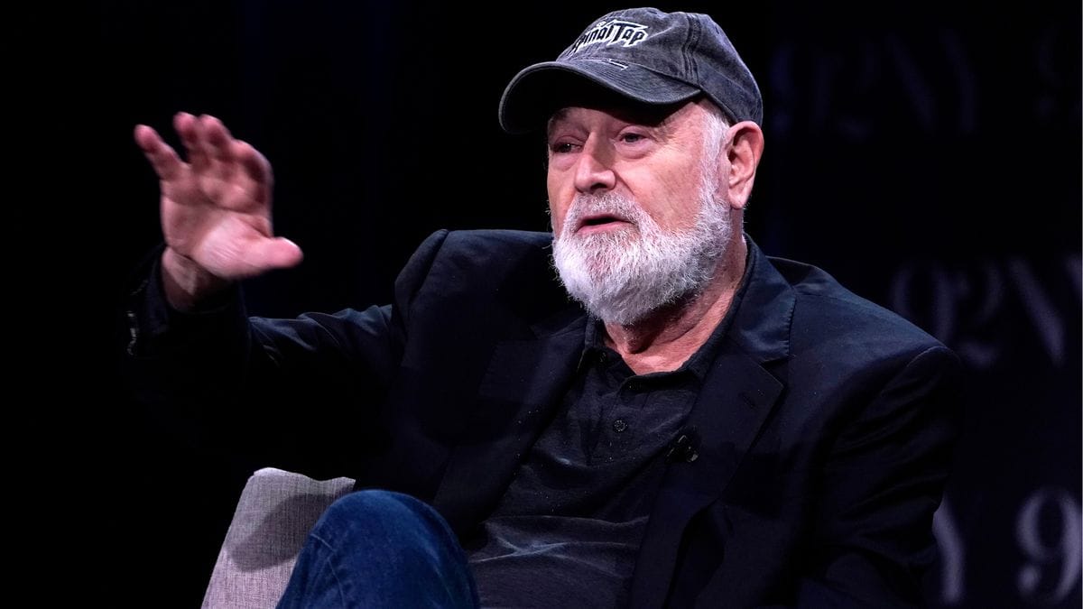 A white man wearing a dark hat that says SpinalTap speaks while sitting down.