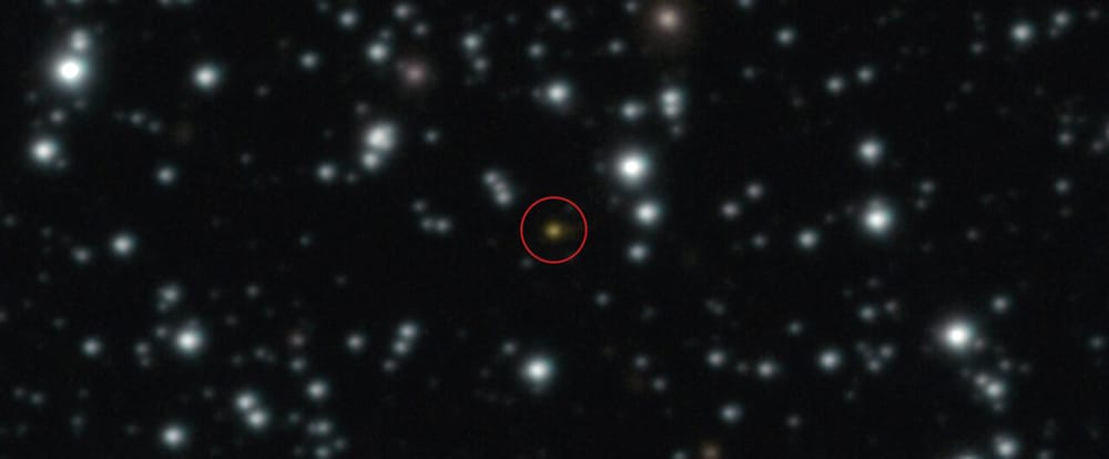 A red dot, circled, sits among hundreds of stars.