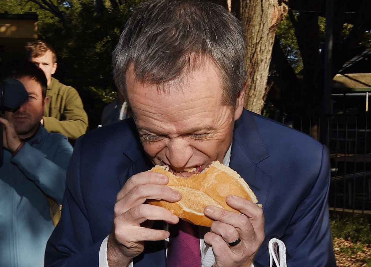 man in suit eats sausage in bread weirdly