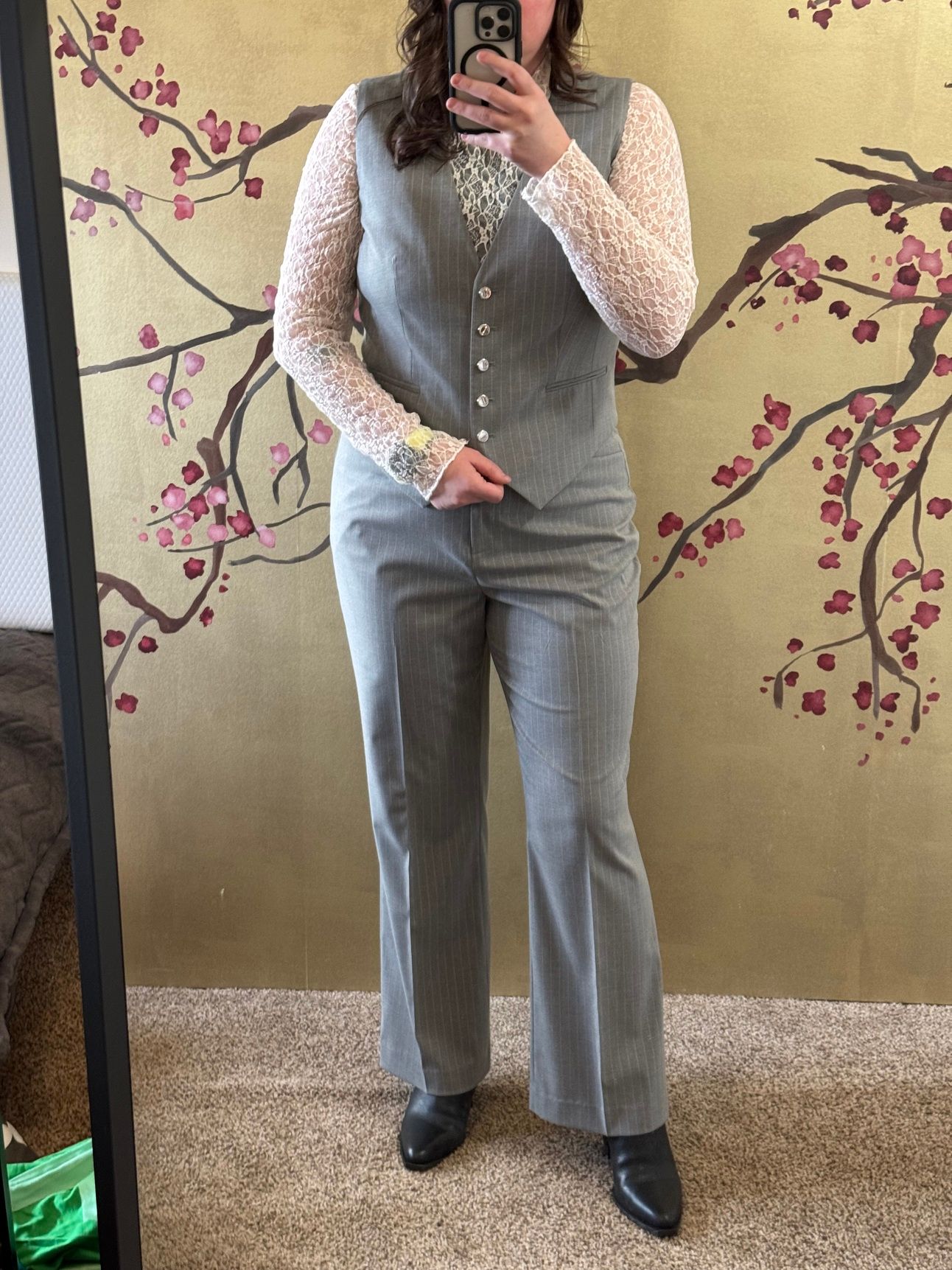 photo of a femine body in white lace top with pinstripe vest and pants.