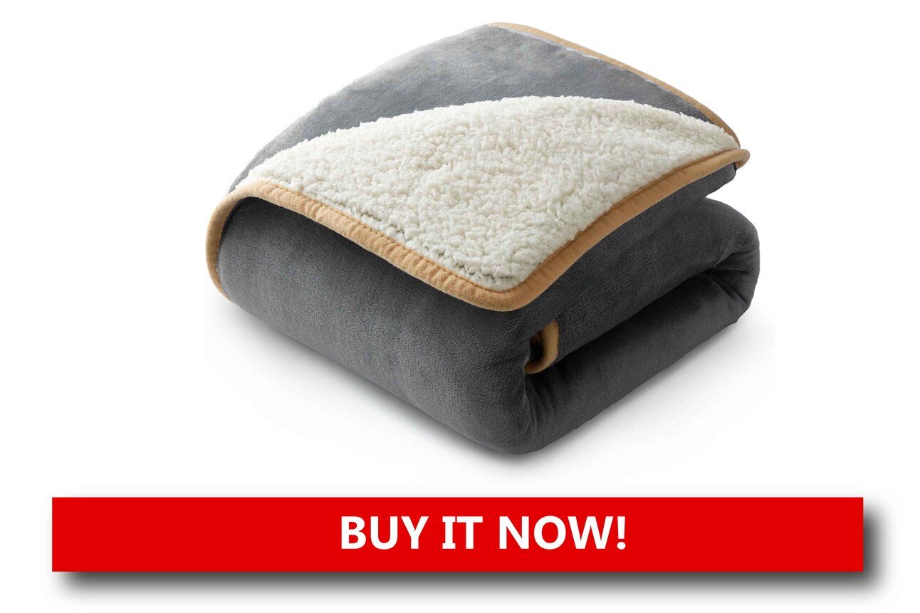 Sherpa-Lined Blankets Alt text: A gray sherpa-lined fleece blanket draped over a couch, with a cat snuggled into the folds and twinkling holiday lights in the background.