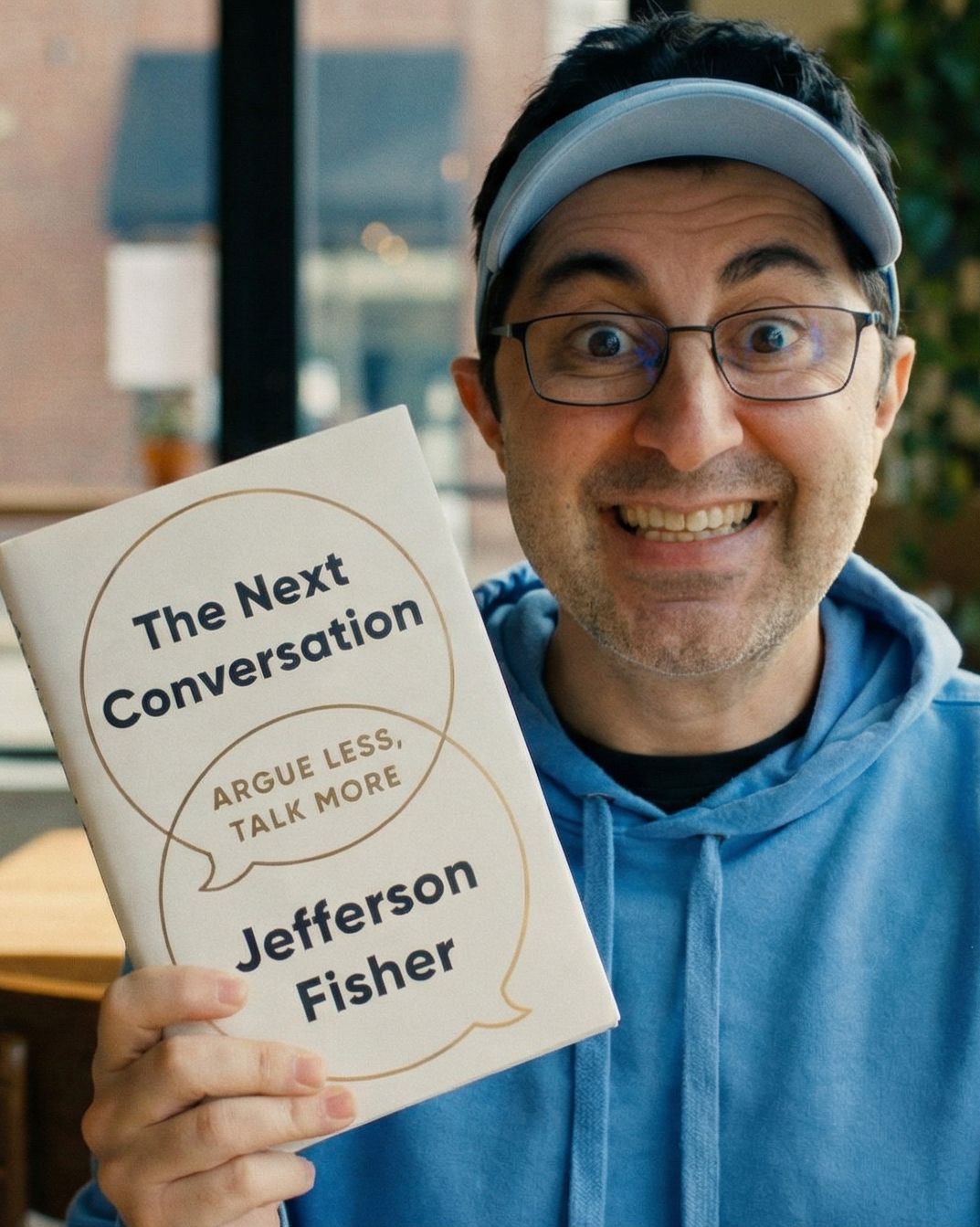 PJ holds the book "The Next Conversation" at a coffee shop.