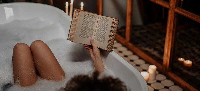 Person reading a book while relaxing in a bath, combining self-care with personal growth.
