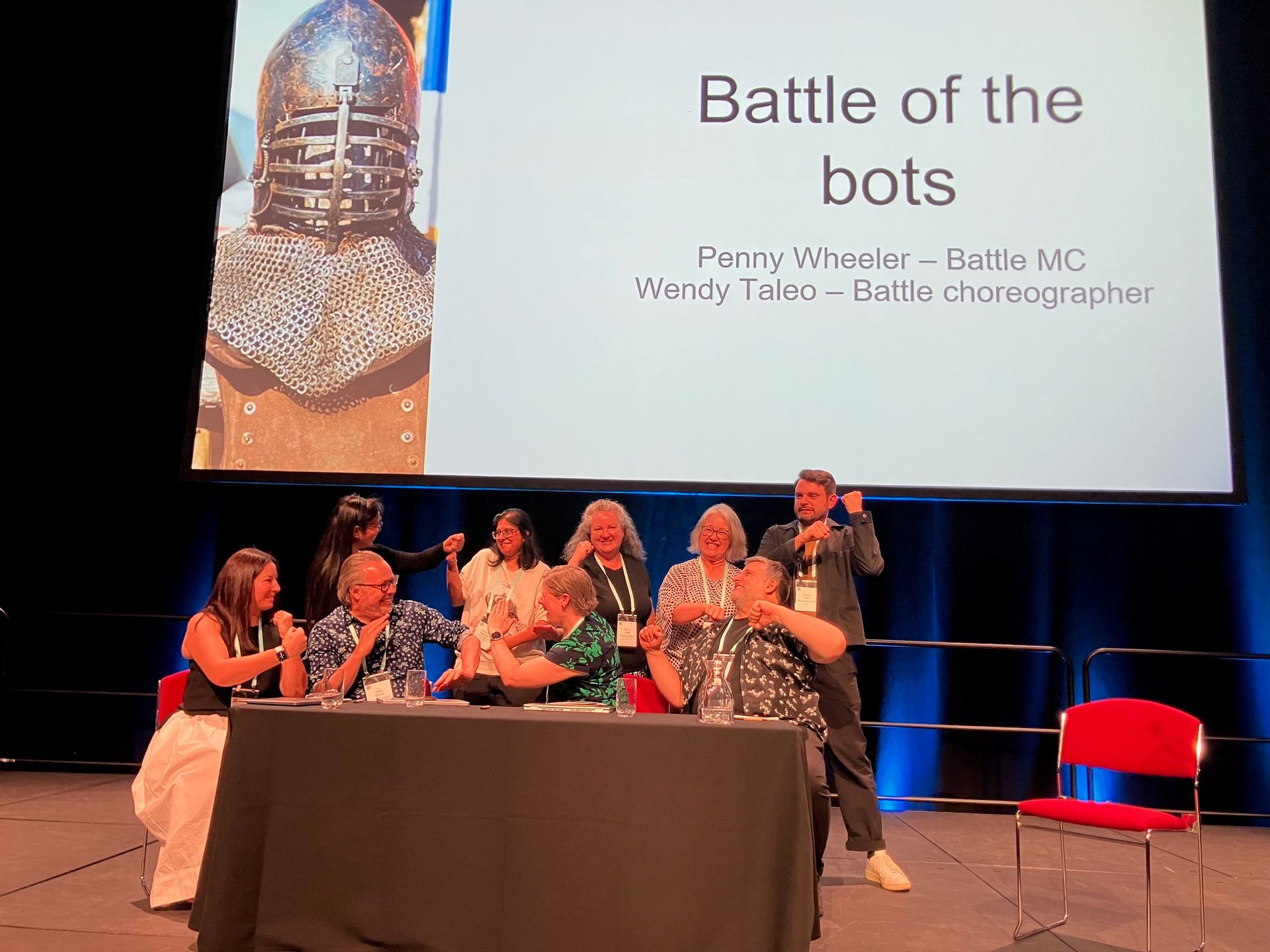 9 people on stage fighting beneath slide for battle of the bots