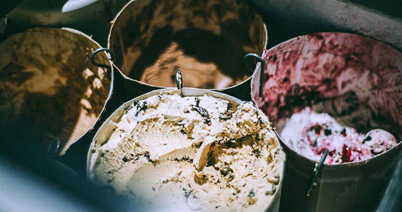 Four buckets of ice cream in a cooler.