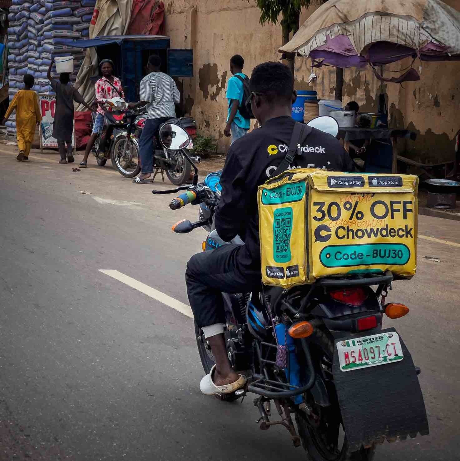 A food delivery rider for Chowdeck on the outskirts of Abuja rides his motorbike , representing the vital chains of economic activity powered by everyday Nigerians